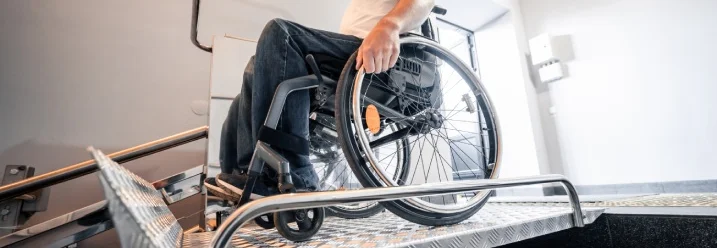 Mensch im Rollstuhl nutzt einen Plattformlift auf einer Treppe.